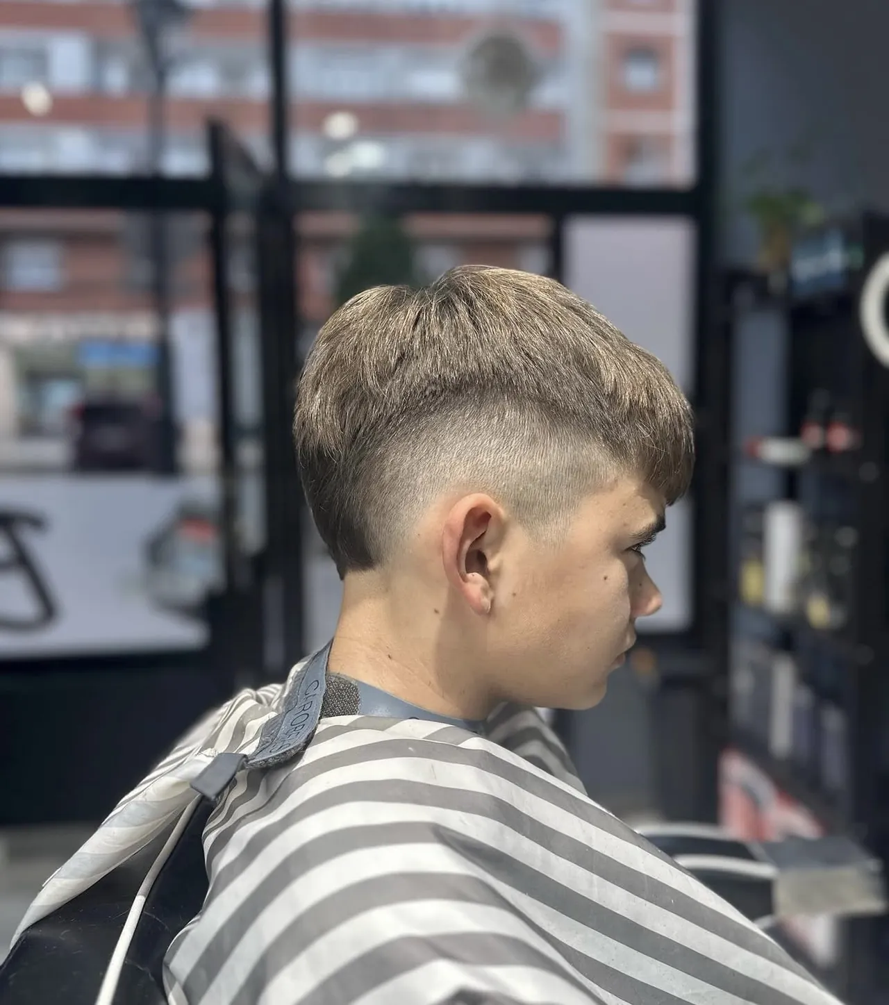 Corte joven con degradado alto y flequillo recto, de perfil